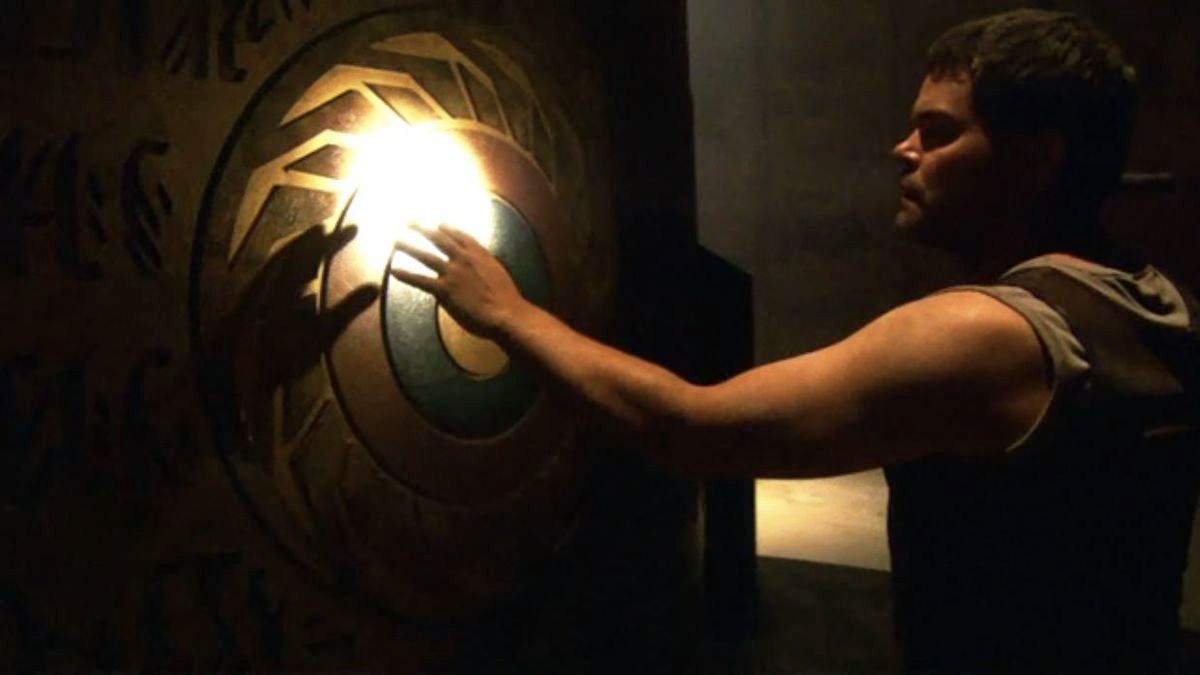 Chief Galen Tyrol (Aaron Douglas) reaches out to touch the carved wall of a temple.