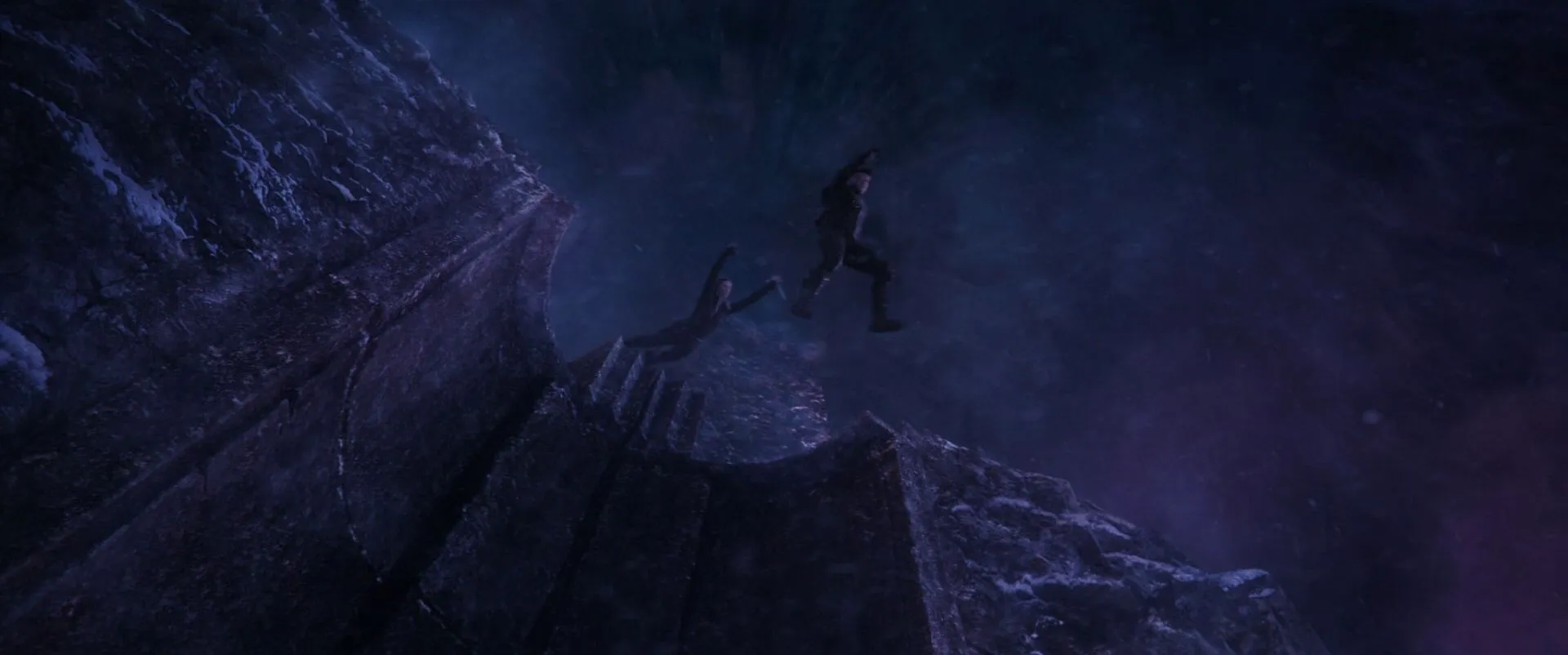 Black Widow dives after Hawkeye as he leaps off the cliff.