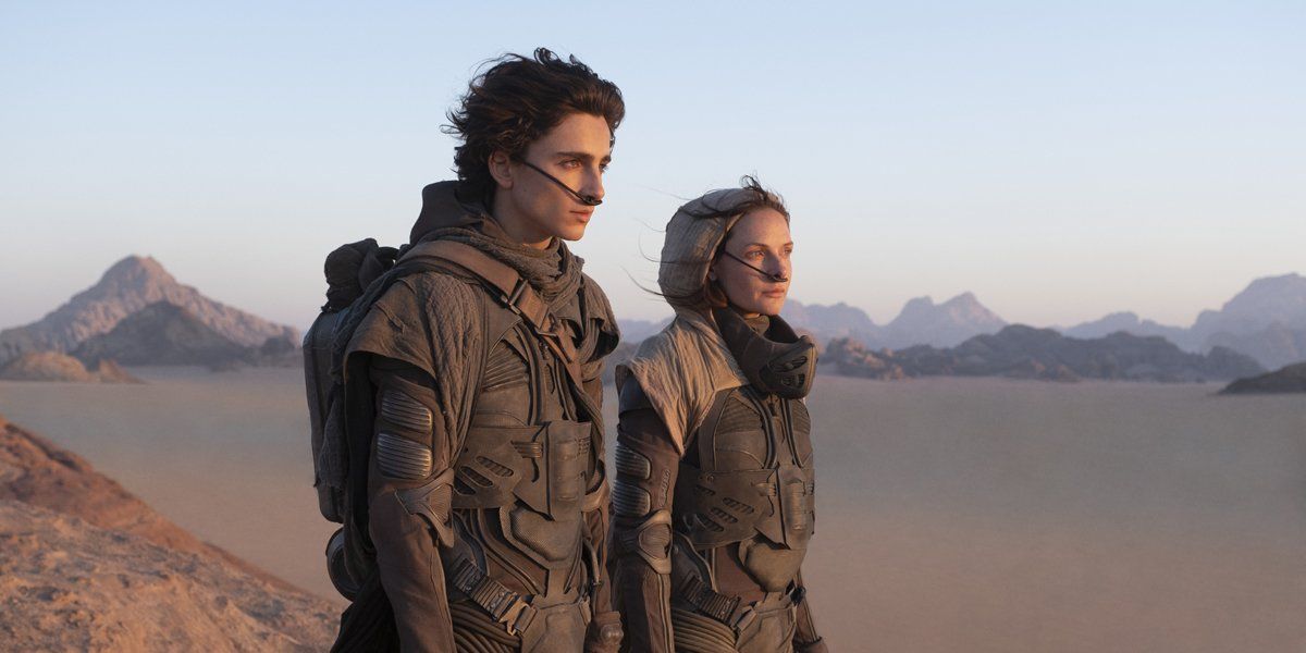 Paul Atreides (Timothée Chalamet) and Lady Jessica (Rebecca Ferguson) stand overlooking the desert in their stillsuits.