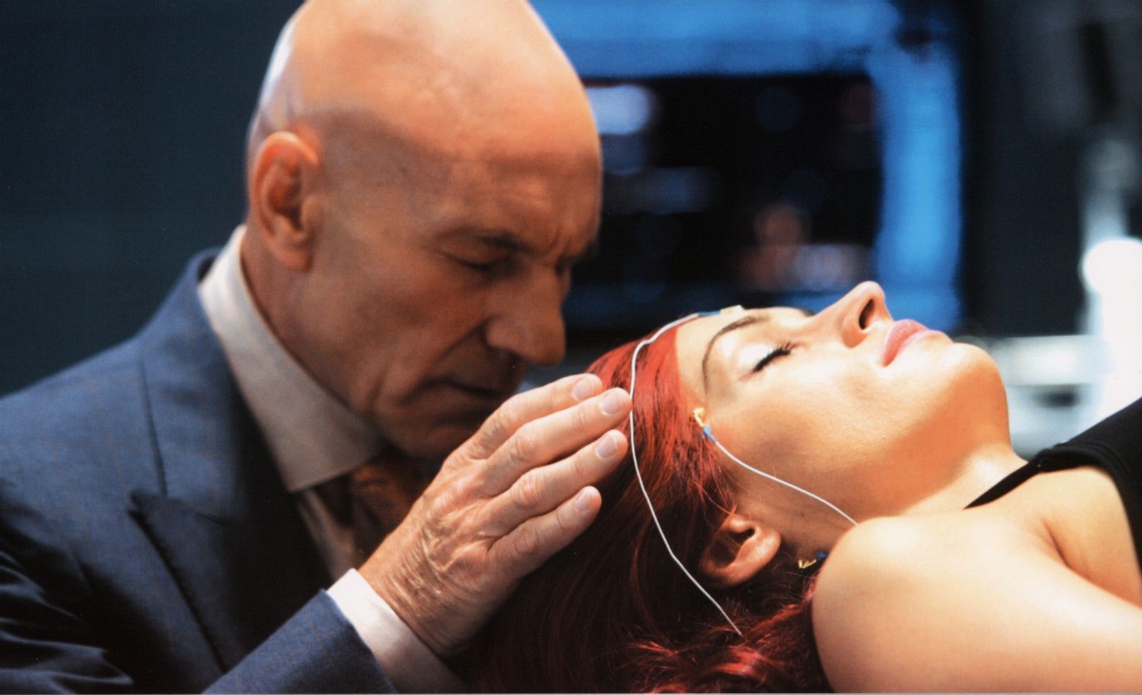 Professor Charles Xavier (Patrick Stewart) has his eyes closed as he places his hands on Jean Grey (Famke Janssen)'s temple.