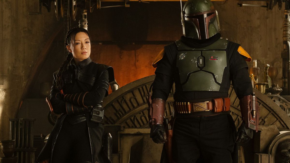 Fennec Shand (Ming-Na Wen) and a fully armored Boba Fett (Temuera Morrison) stand in front of Jabba the Hutt’s vacant throne.