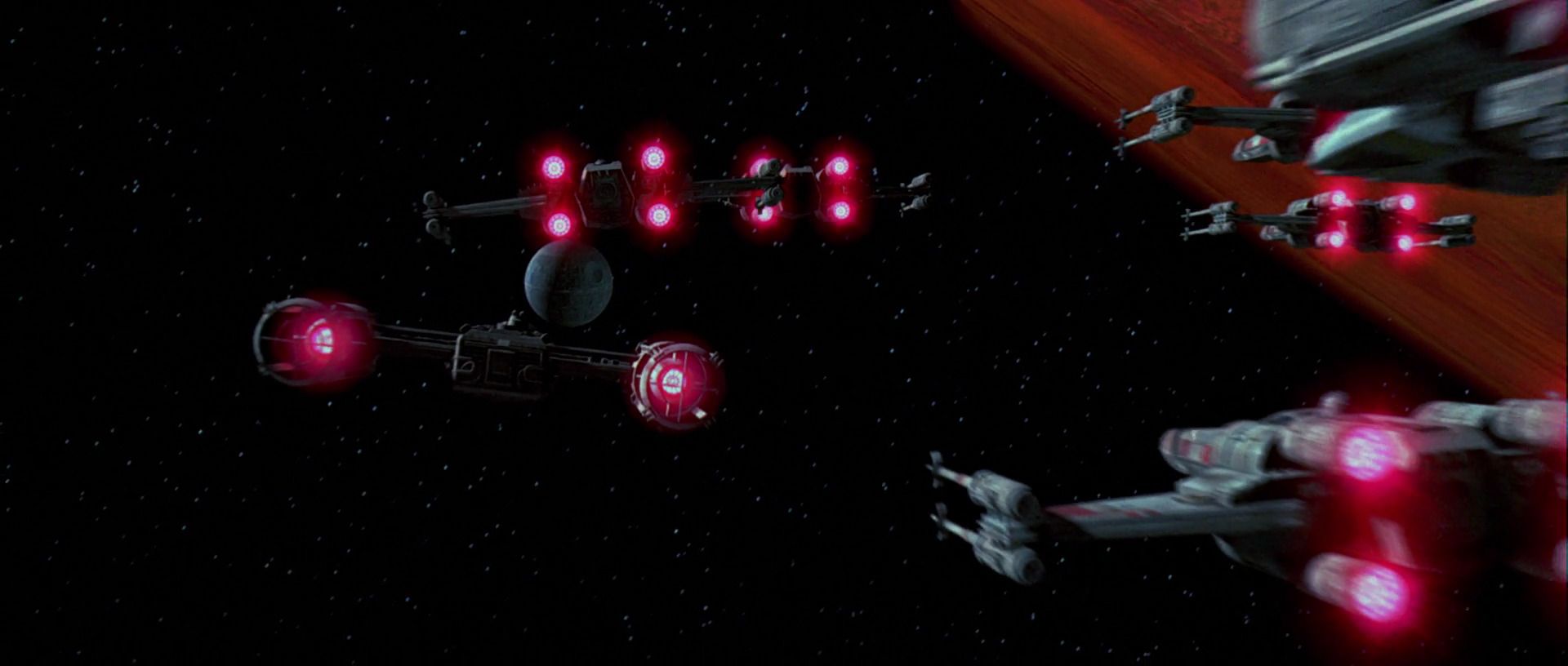 Y-Wings and X-Wings pictured from behind with their engines glowing red as they fly towards the Death Star.