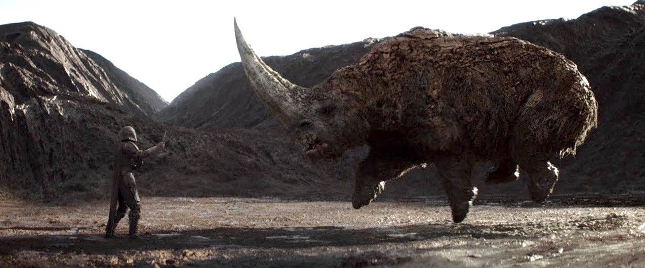 Viewed side on as the rhino-like Mudhorn is raised into the air. Din Djarin (Pedro Pascal) raises his hand to it.