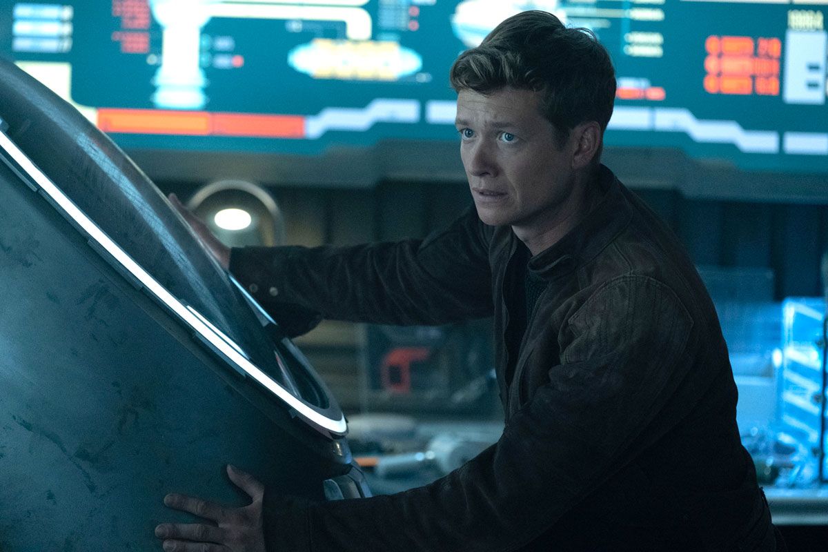 Jack Crusher (Ed Speleers) stands with his hands on the stasis chamber.