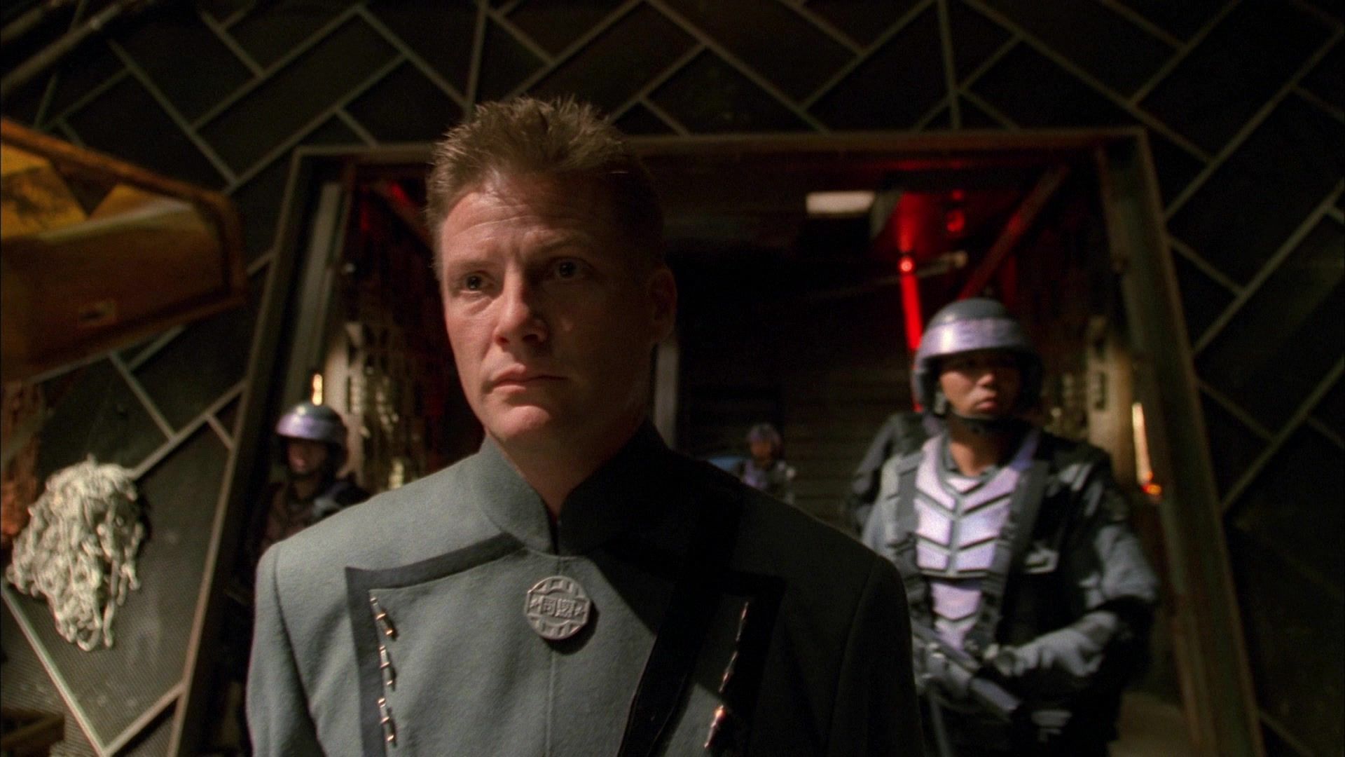 The uniformed Commander Harken (Doug Savant) flanked by soldiers.