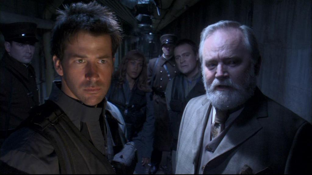 Hoffan Chancellor Druhin (Alan Scarfe)with Major John Sheppard (Joe Flanigan), Teyla Emmagan (Rachel Luttrell), and Rodney McKay (David Hewlett) are shown through an underground vault.