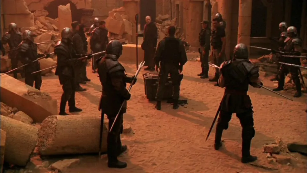 Ori soldiers with staff weapons form a circle around Cameron Mitchell (Ben Browder).