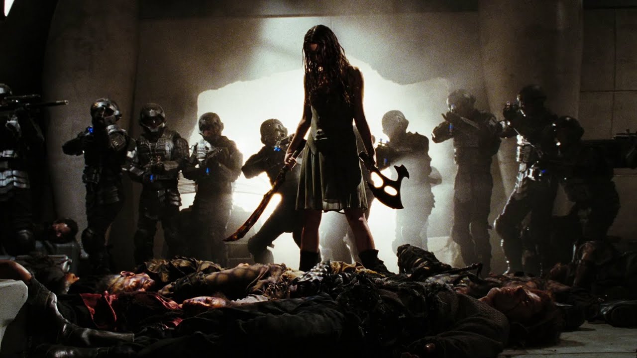 River Tam stands surrounded by armed soldiers. She is holding an axe-like weapon and a curved sword-like weapon, and wearing a floaty dress. 