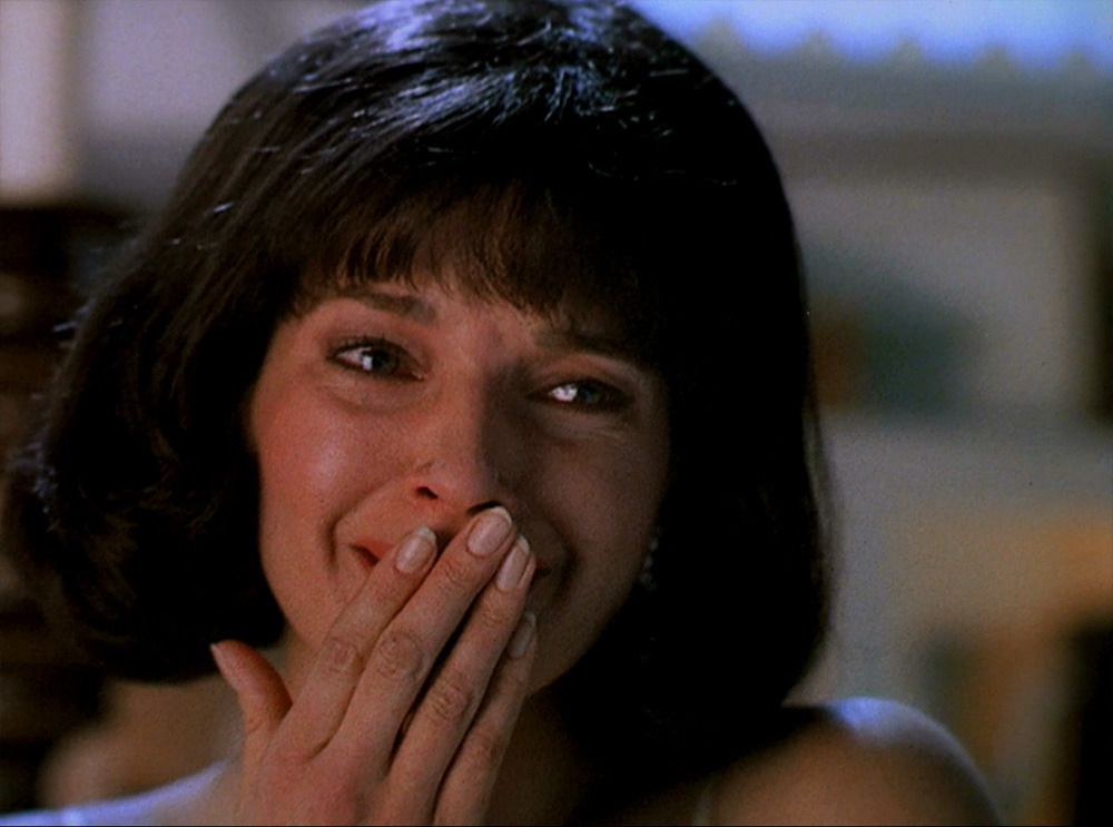 Beth Calavicci (Susan Diol) brings her hand to her mouth.