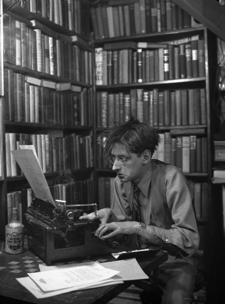 A young Robert Bloch is hunched over his typewriter.
