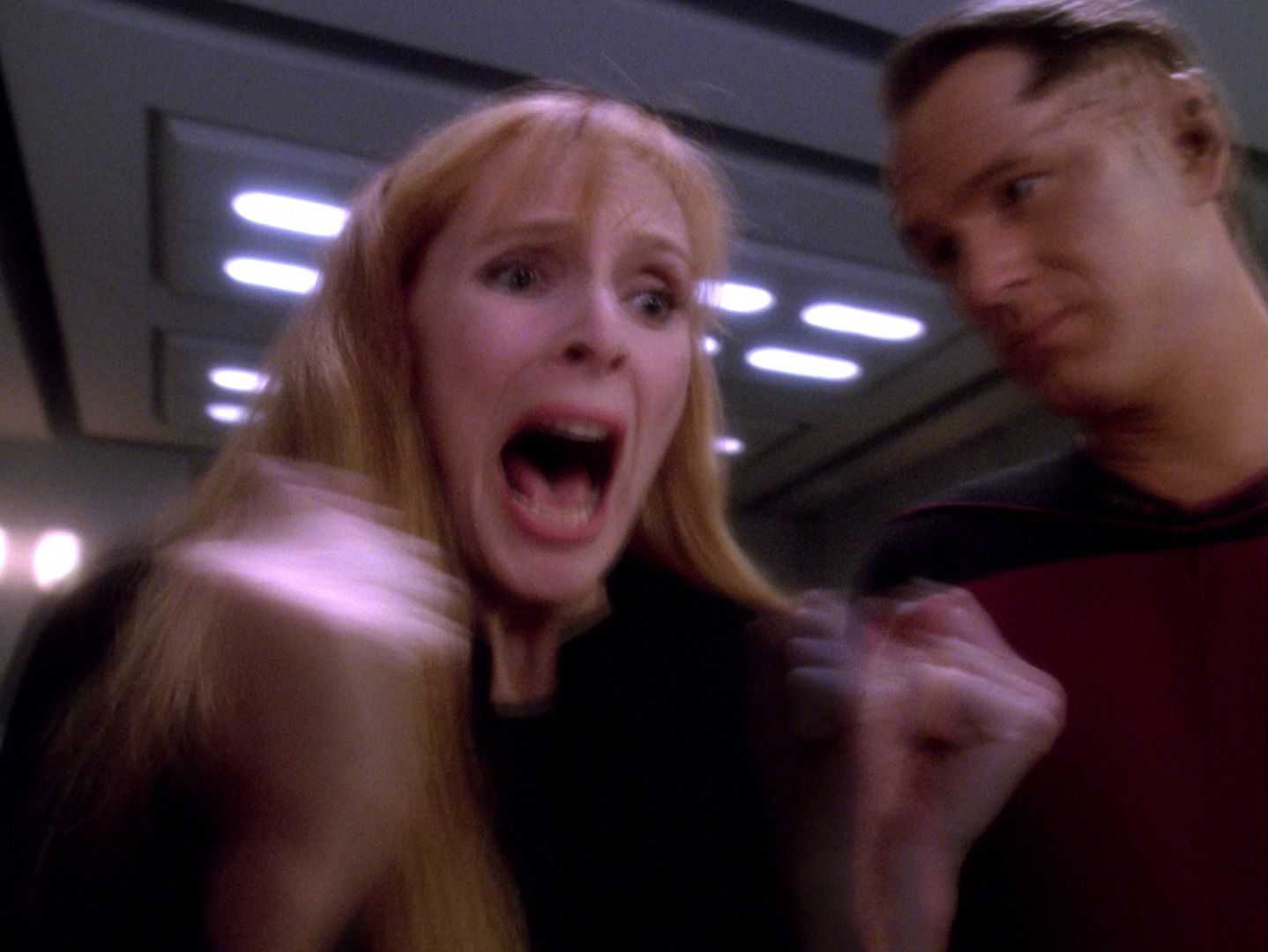 Dr. Beverly Crusher (Gates McFadden) screams as Jev (Ben Lemon) leans in.