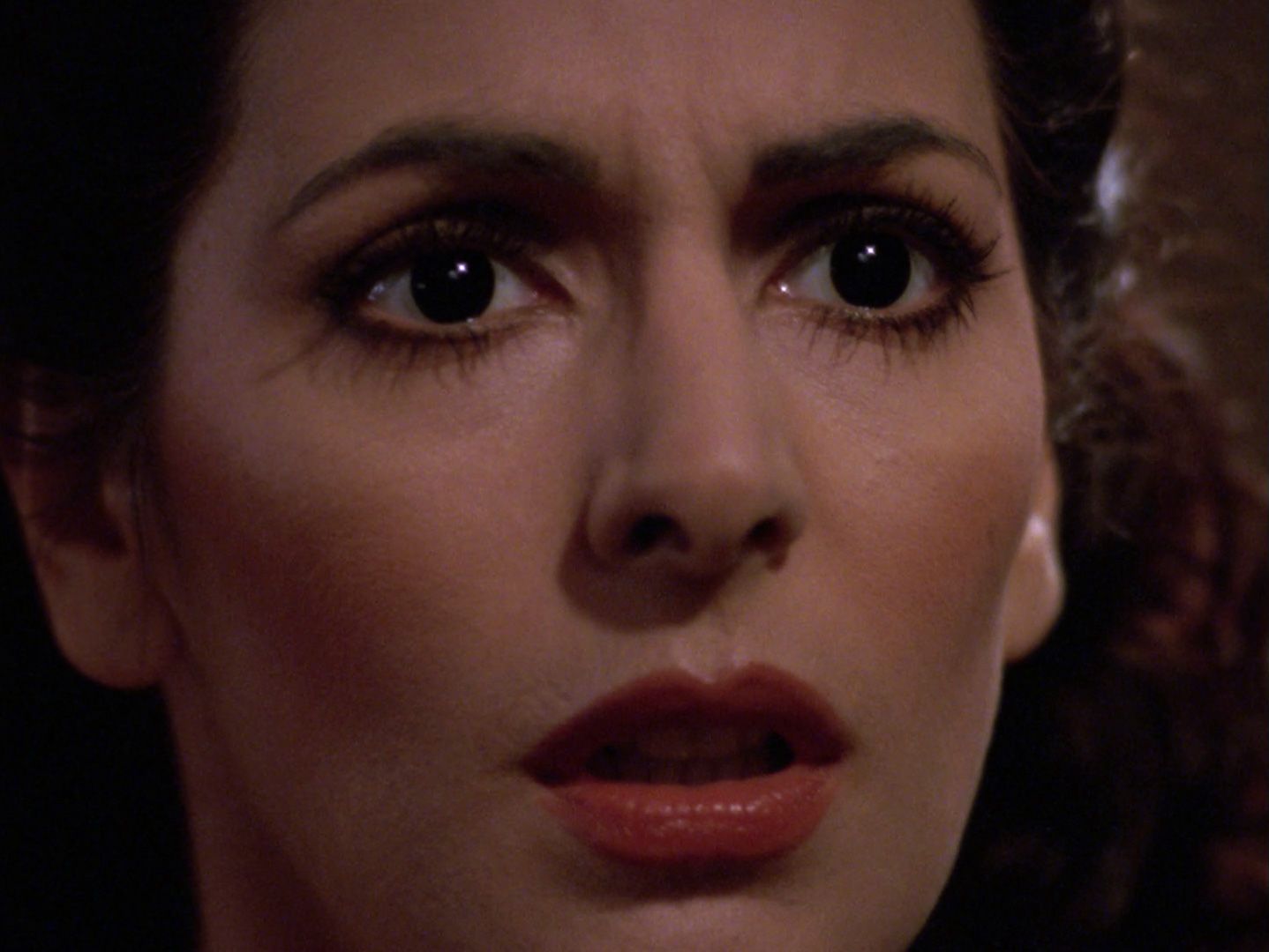 A close-up on a shocked Deanna Troi (Marina Sirtis).