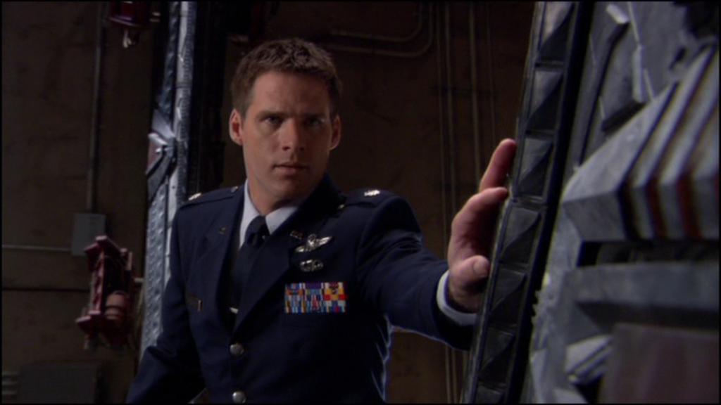 Lt. Col. Cameron Mitchell (Ben Browder) wears dress blues and places his hand on the Stargate.