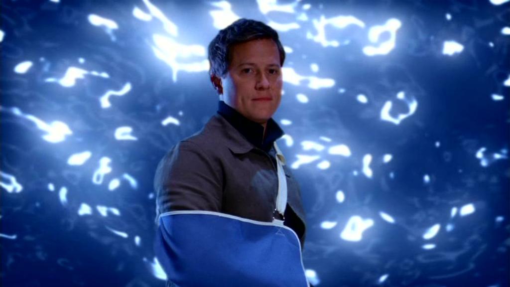 Jonas Quinn (Corin Nemec) stands in front of the gate with his arm in a sling.