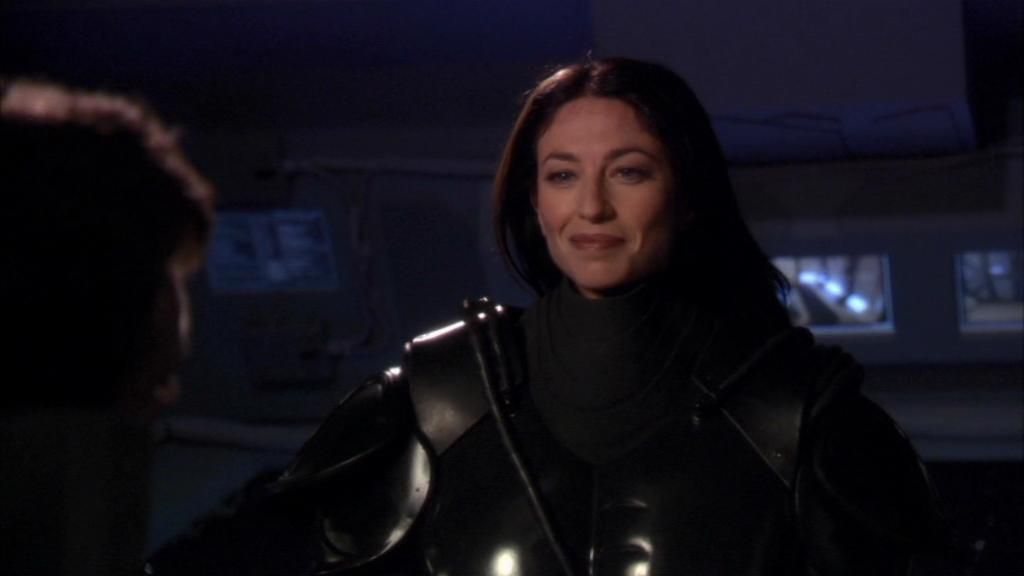 Vala Mal Doran (Claudia Black) removes her helmet and smiles.