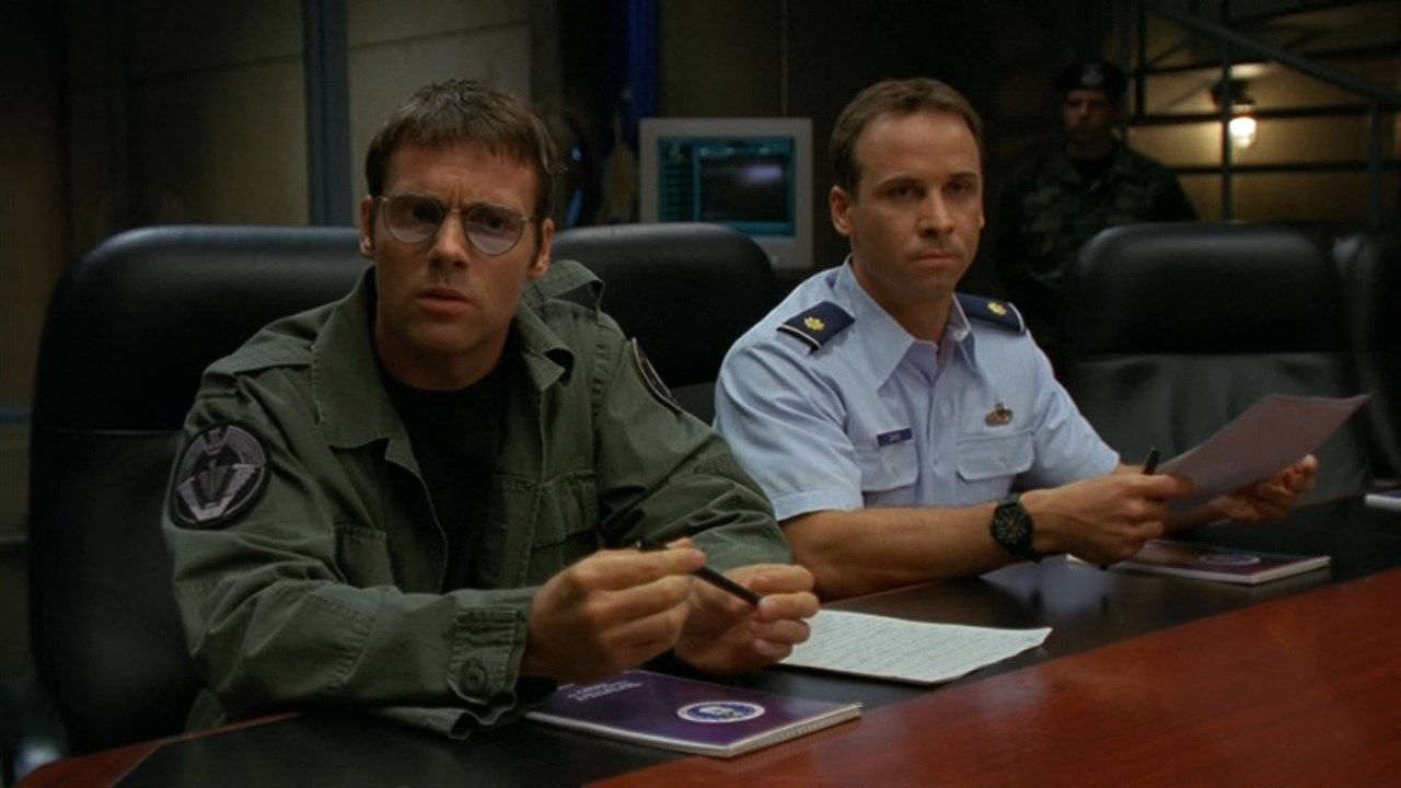 Daniel Jackson (Michael Shanks) and Major Paul Davis (Colin Cunningham) in the Stargate SG-1 episode ‘Tangent’. Jackson and Davis are seated at the conference table in Stargate Command.