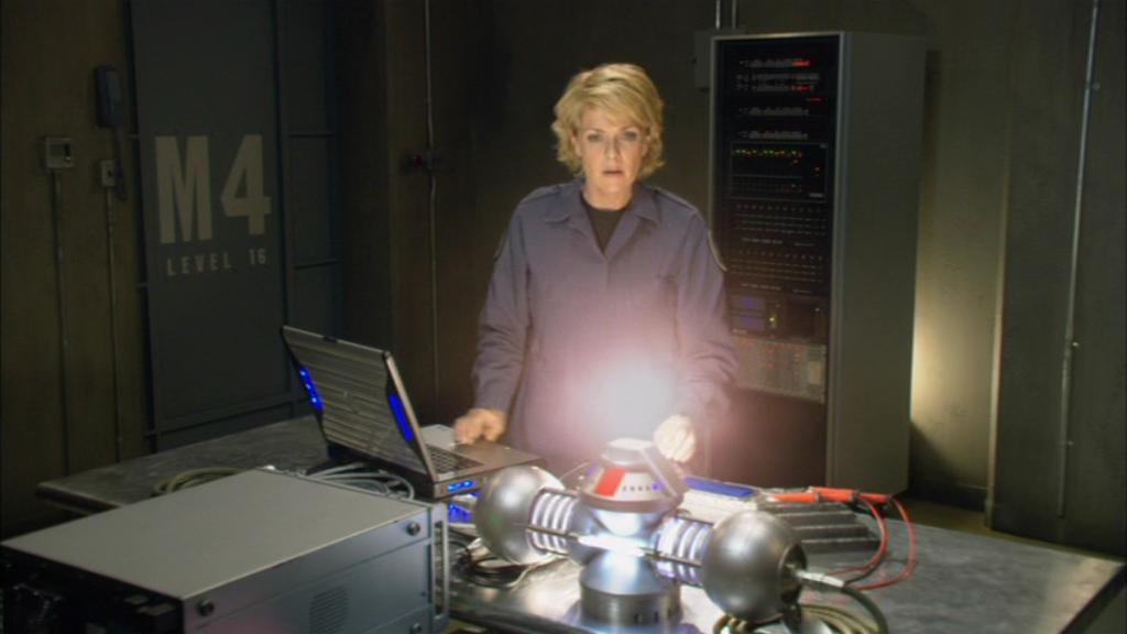 Samantha Carter looks down at the glowing device called Arthur's Mantle as it begins to power up.