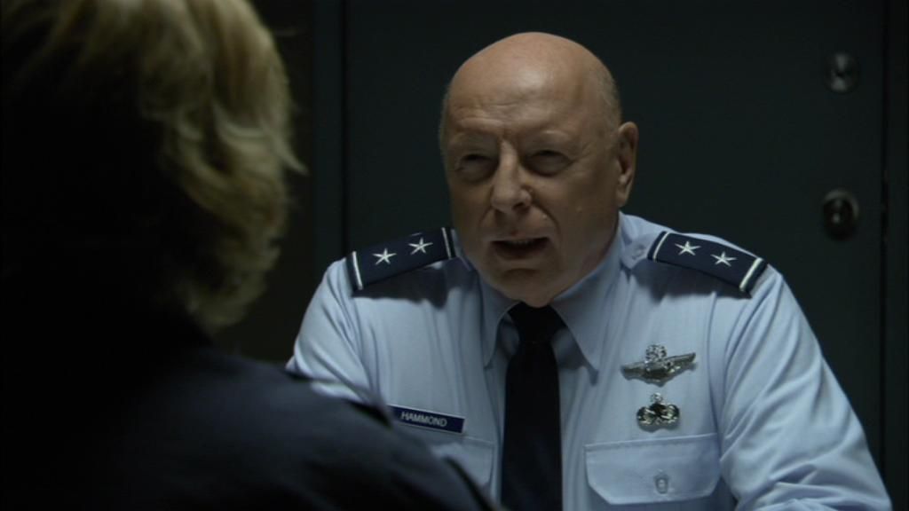 A skeptical General Hammond speaks to Samantha Carter, who has her back to the camera.