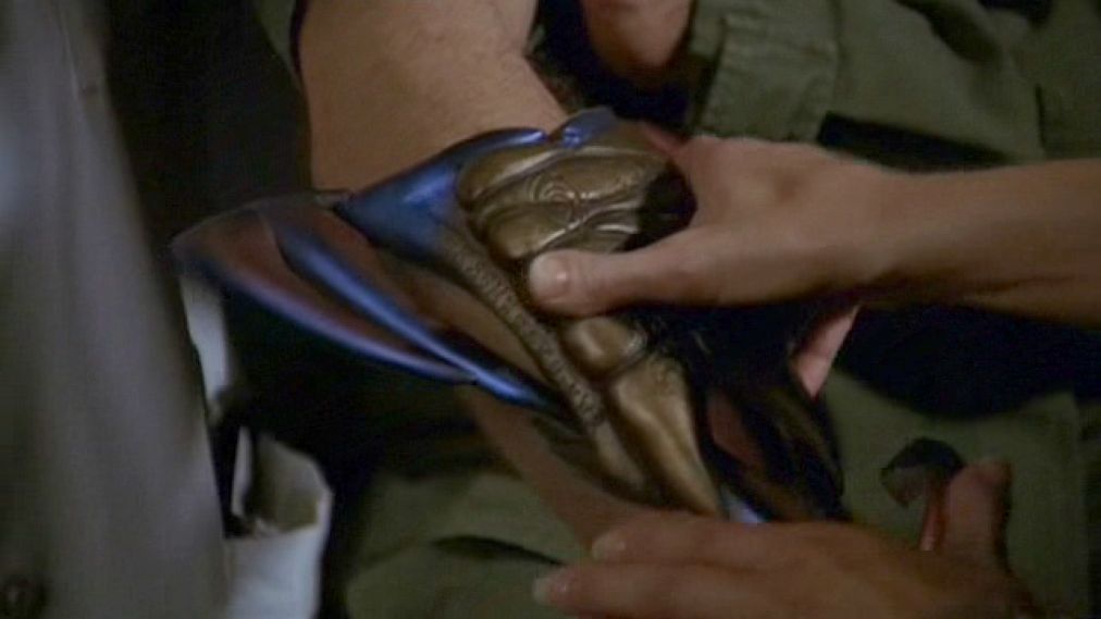 Jack O’Neill (Richard Dean Anderson) raises the armband to his shoulder.