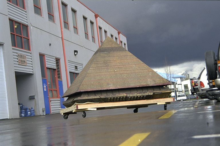 A model pyramid from the Stargate movie is mounted on a trolly and is being wheeled across a car park.