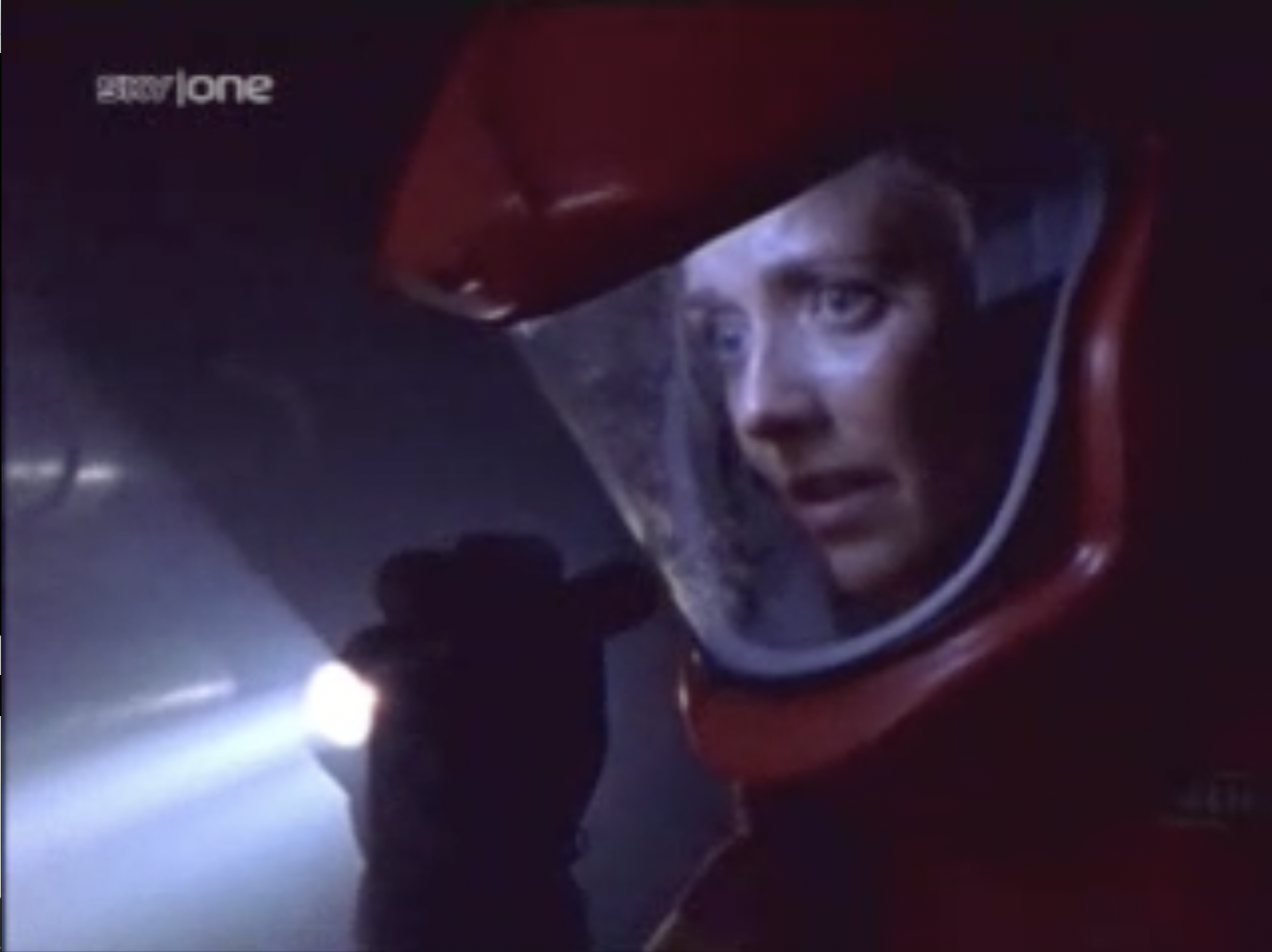 Commander Kate Girard (Amanda Tapping) wearing a red environment suit.