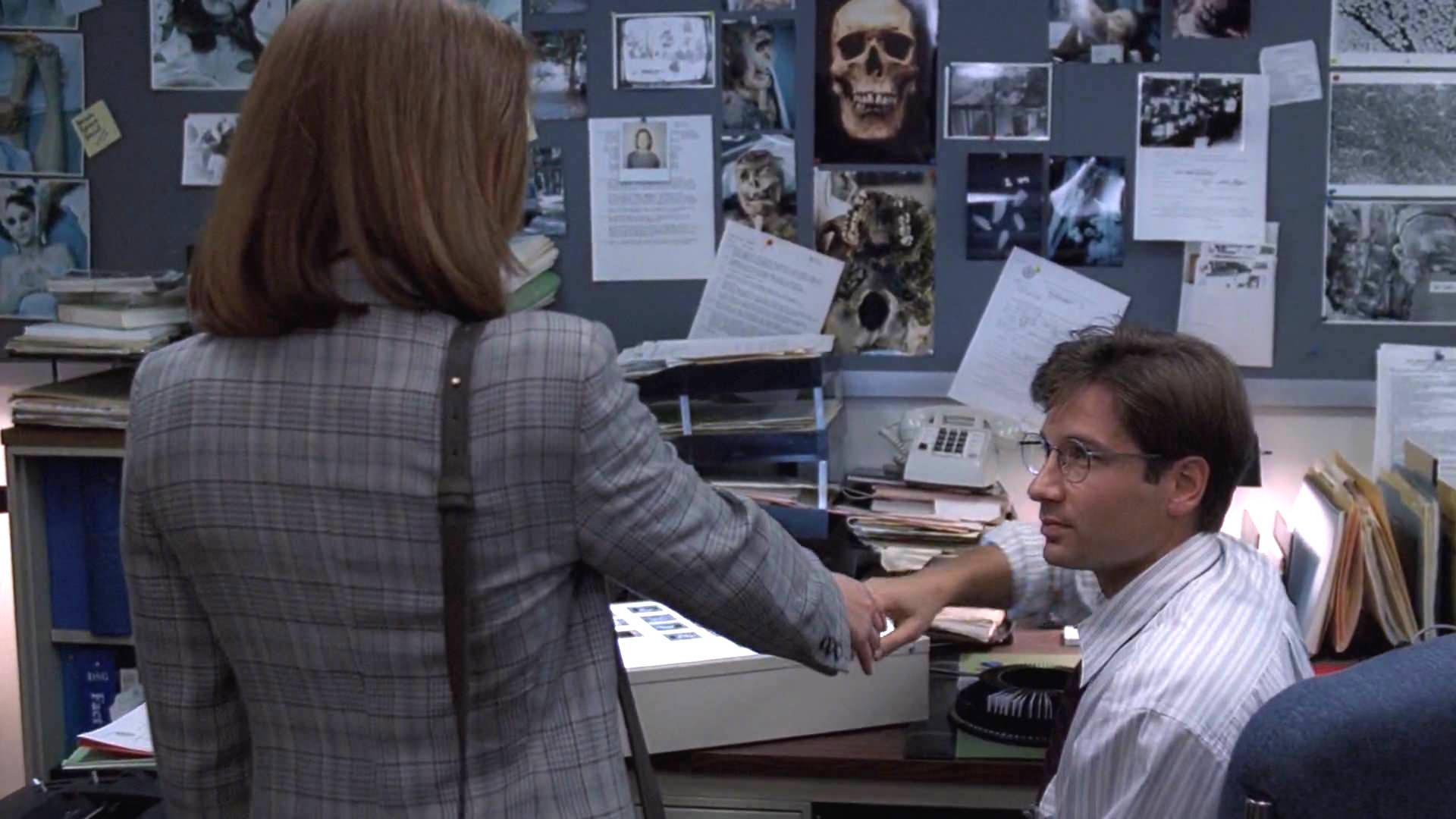 Dana Scully (Gillian Anderson) introduces herself to Fox Mulder (David Duchovny) in The X-Files ‘Pilot’ episode (S1, Ep1). Chris Carter, the creator of The X-Files, fought back against any romantic relationship developing between Mulder and Scully. | 20th Century Fox, 1994.